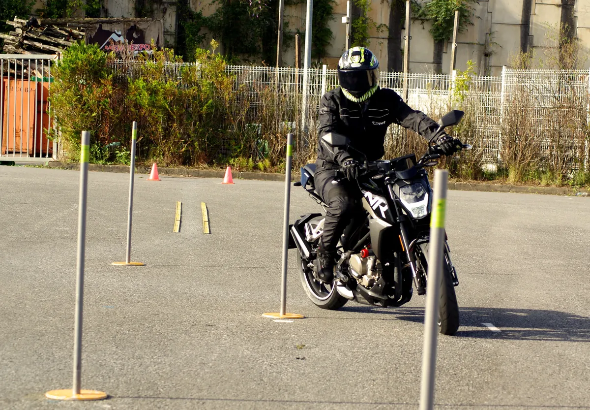Alumna de moto de Autoescuela Donosti con chaleco de prácticas en un parque